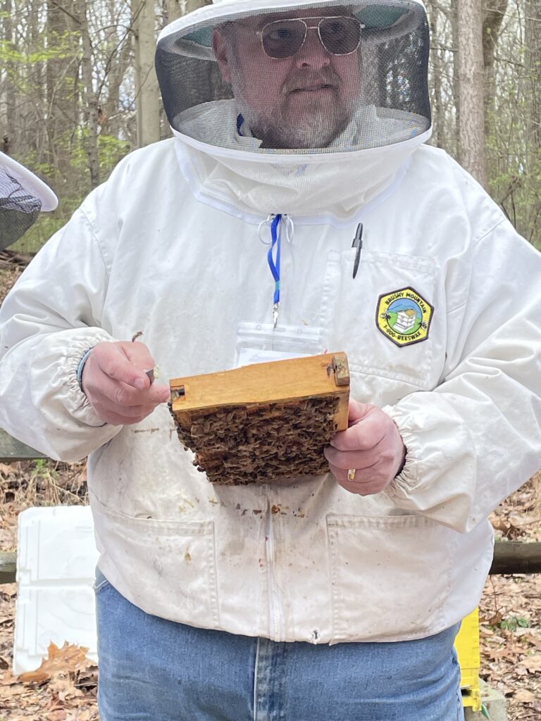 Jim Fraser in bee suit holding brood frame